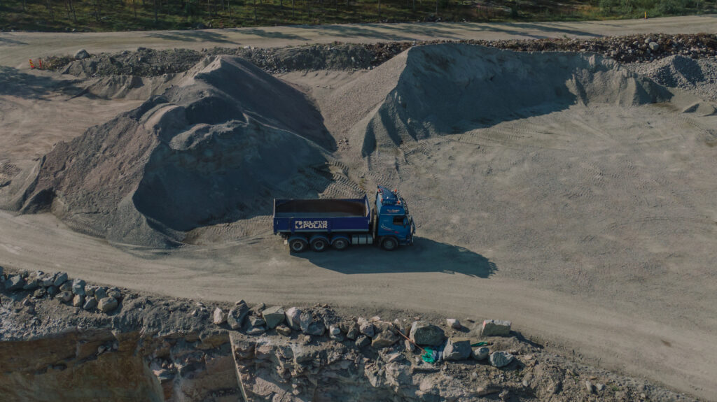 Murskeet ovat kivi- ja maa-ainesta, lintuperspektiivissä olevassa kuvassa sinisen kuorma-auto kuljettamassa mursketta ottopaikalta.
