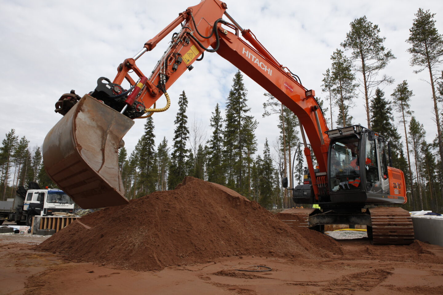 Maansiirto Oulu, kaivinkone työskentelemässä omakotitalotyömaalla, etualalla hiekkakasa.